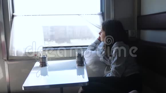铁路旅行概念小女孩望着窗外在车厢里喝茶穿深色衣服的女孩喝酒视频的预览图