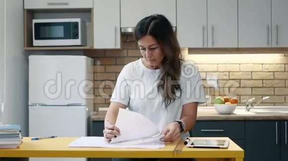 女建筑师在家里厨房里拿着文件工作视频的预览图