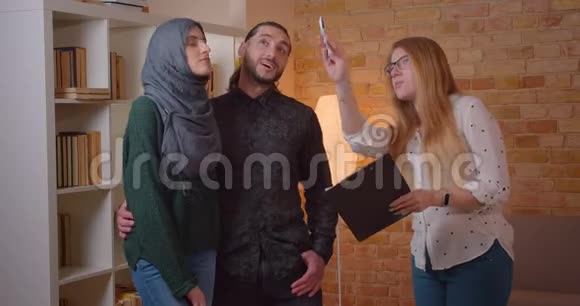 一对年轻快乐的穆斯林夫妇在一间新买的公寓里兴高采烈地拥抱在室内与雷特交谈视频的预览图