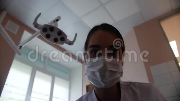 一个戴着面具的女牙医把灯的光引到相机上牙医办公室视频的预览图