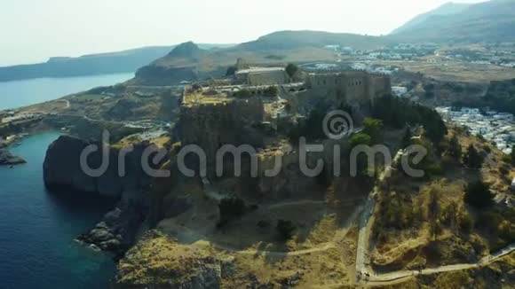 鸟瞰希腊小镇林多斯罗德斯和卫城周围是白色的房子和蓝色的海湾视频的预览图