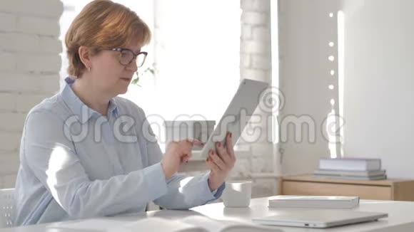工作场所的老妇人通过平板电脑在线视频聊天视频的预览图