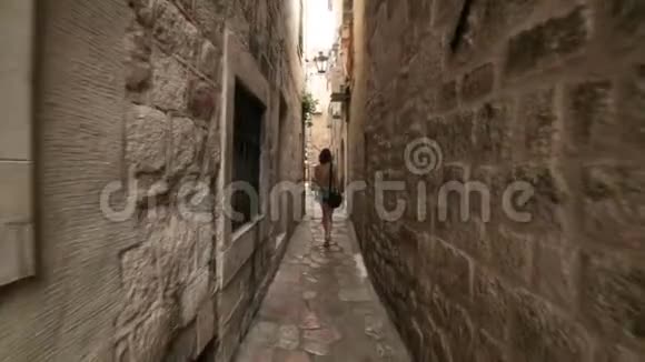 旅游女孩沿着地中海老镇或黑山城市狭窄的鹅卵石街道行走就像意大利或视频的预览图