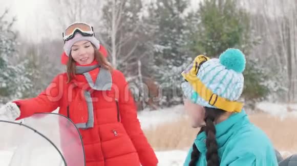 冬天两个穿着五颜六色夹克的年轻女子谈笑风生然后戴上眼镜准备乘车视频的预览图