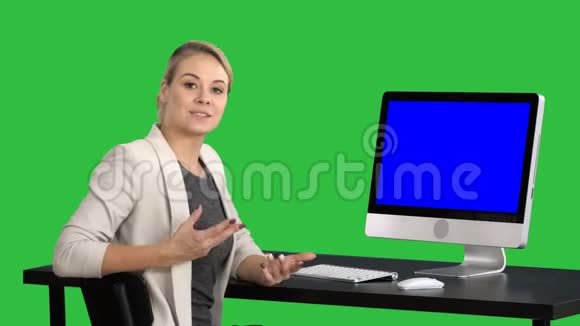 年轻漂亮的女士在对着镜头说话在电脑屏幕上显示一些东西绿色屏幕Chroma视频的预览图