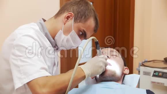 男性牙医在治疗男性患者牙齿的过程中在诊所的牙医接待处视频的预览图