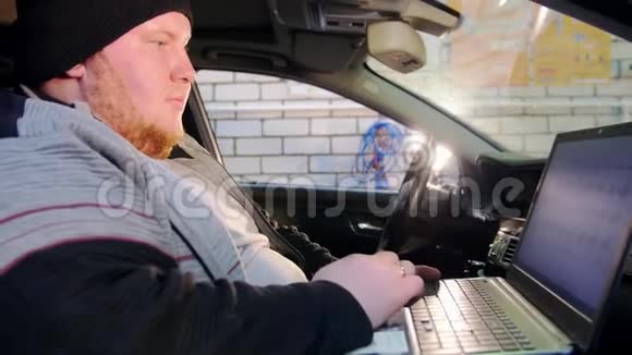汽车服务厚厚的机械师坐在车里用笔记本电脑工作视频的预览图