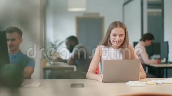 兴奋的商务女性在办公室的笔记本电脑上享受好消息视频的预览图