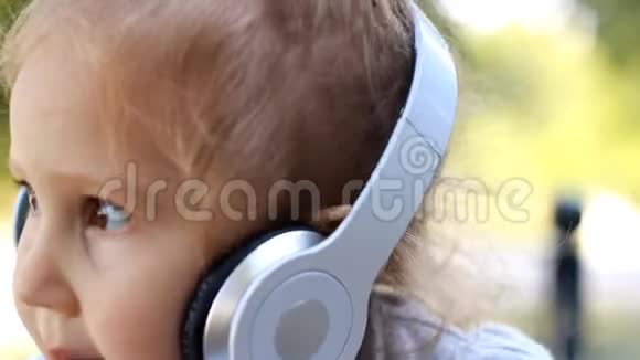 可爱的儿童女孩戴着耳机听音乐和唱歌肖像特写视频的预览图