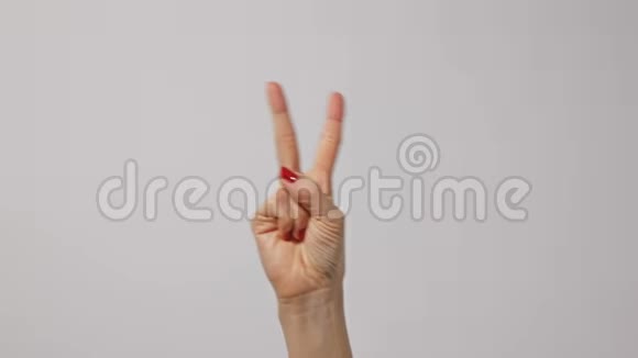 女人举起两个手指表示和平或胜利的象征或字母V女人一只手举起两个手指视频的预览图