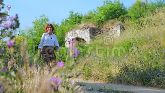 一个红头发的乡村女孩沿着乡间的土路或小径散步视频的预览图