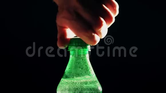 男子打开绿色塑料瓶的泡沫苏打水在黑色背景下视频的预览图