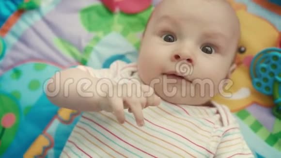 婴儿在彩色垫子上看相机的肖像合上可爱的娃娃脸视频的预览图