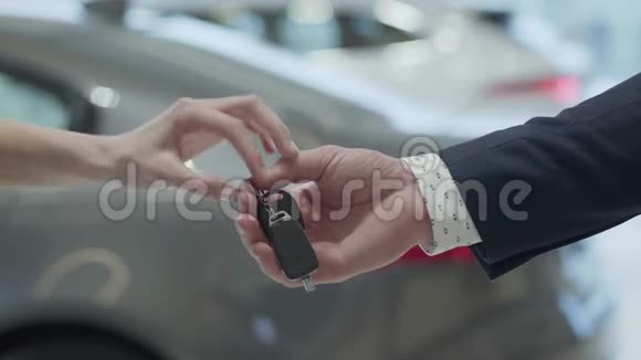 男性手把车钥匙交给家庭手在汽车经销商关闭不承认的汽车销售商和一个视频的预览图