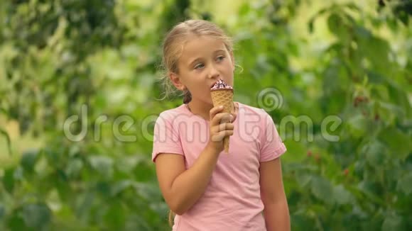在绿色树叶背景下吃冰淇淋的女孩视频的预览图