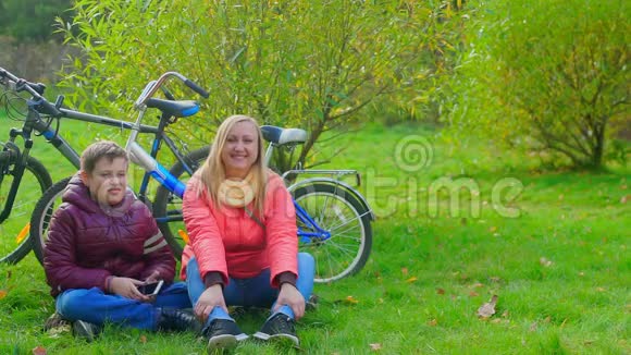 与母亲坐在草地上的少年视频的预览图
