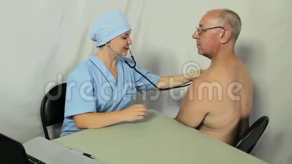 一位女医生坐在他的办公桌前用听诊器听病人胸部镜头移向小车视频的预览图