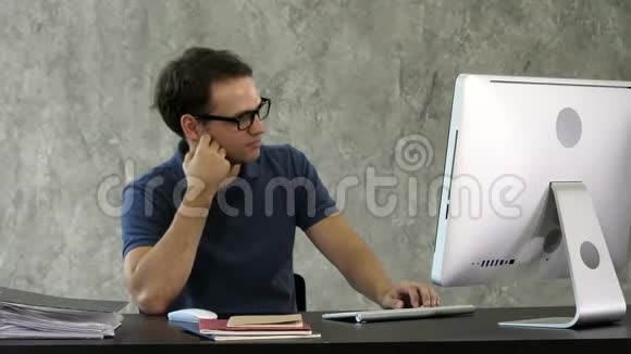 无聊的年轻人在电脑前的桌子上视频的预览图
