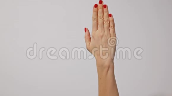 美丽的年轻女子她的手上有鲜红的指甲一只手轻轻地按摩另一只手被隔离在灰色的背景上视频的预览图