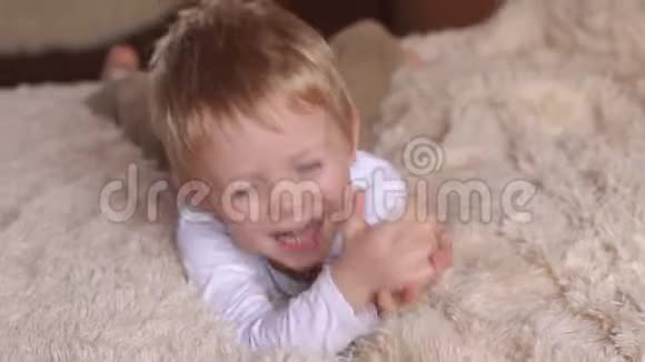 一个快乐的小男孩在床上玩耍大笑和展示语言视频的预览图