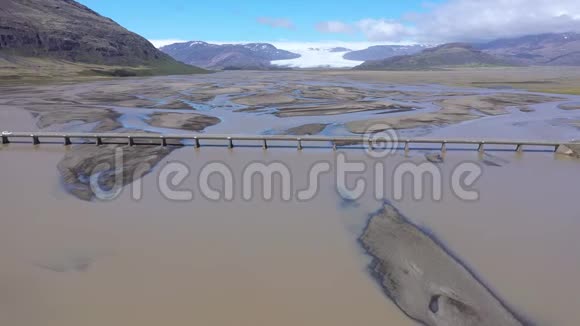 无人驾驶飞机在冰岛的一条河上通过一座桥运送冰川沉积物视频的预览图
