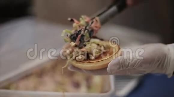 在手套里做饭把准备好的蔬菜沙拉放在面包上做汉堡包快餐露天活动视频的预览图
