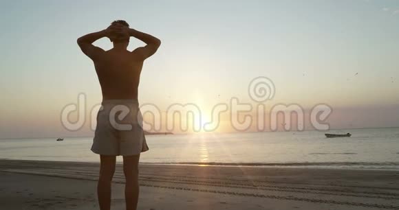 年轻的白种人在平静的海边放松迎接日出冥想自然视频的预览图