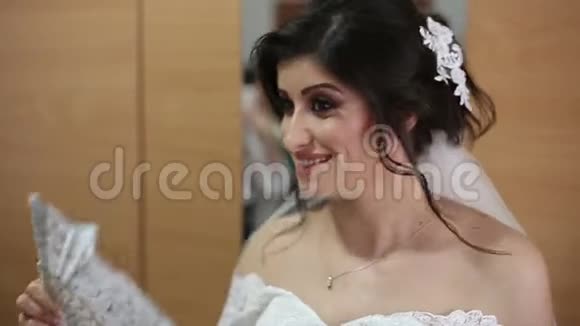 年轻漂亮的新娘穿着白色婚纱的扇子视频的预览图
