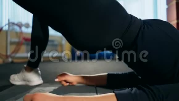 女孩在健身房摇她躺在地板上的臀部锻炼视频的预览图