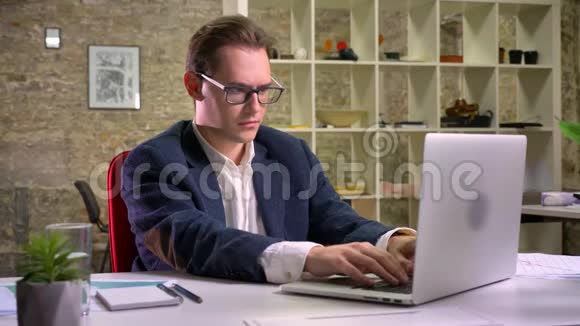 可爱时尚的白种人男性专注于工作用笔记本电脑打字靠办公室喝水休息视频的预览图