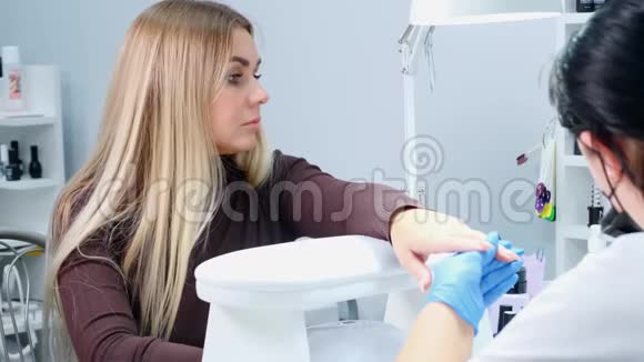 美甲医生正在一家美容院给客户的指甲涂上凝胶抛光剂竖起钉子刀片女孩失修指甲视频的预览图