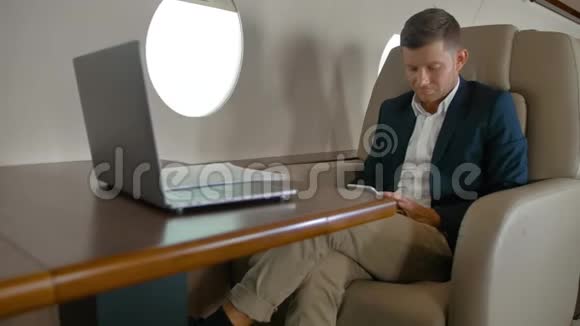 商务人士坐在舒适的扶手椅上坐在私人飞机舱里聊天视频的预览图