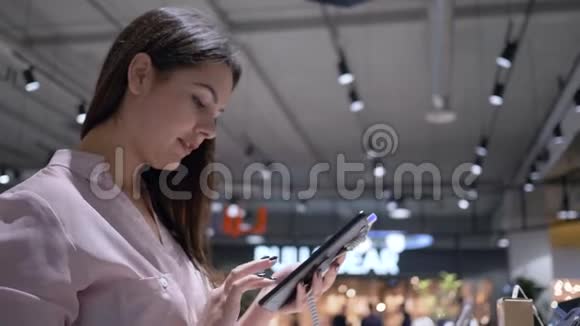 电子商店的小玩意陈列室客户使用带有触摸屏的现代平板电脑视频的预览图