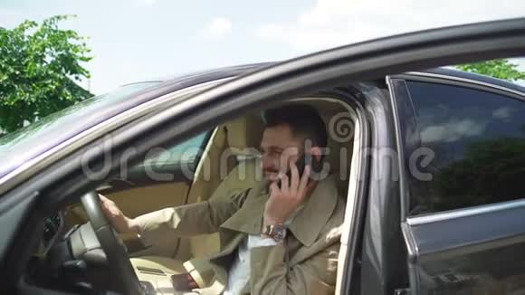 一个英俊的商人用他的手机开着一辆现代化的车视频的预览图