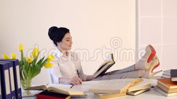 女人坐在工作场所边看书边笑视频的预览图