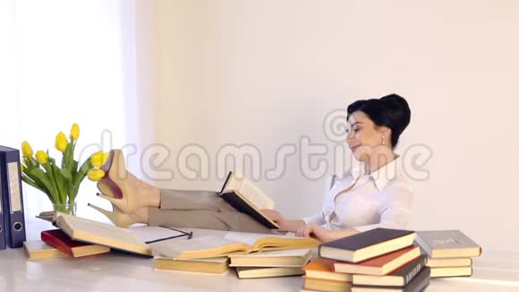 女人坐在工作场所边看书边笑视频的预览图