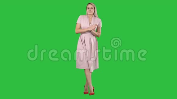 可爱的女孩穿着粉红色连衣裙与相机交谈在绿色屏幕上微笑Chroma键视频的预览图