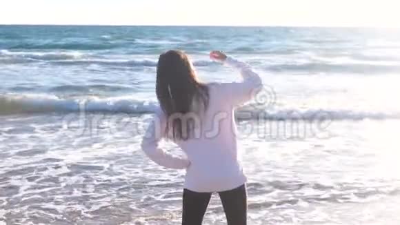 女人正在伸展和做瑜伽站立侧开放软管在沙滩上与波浪后景视频的预览图