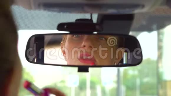女孩坐在车里嘴唇上涂着口红她照镜子女孩化妆了几层她看着视频的预览图
