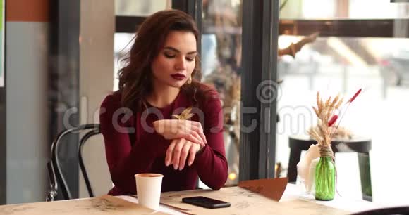 忙碌的红衣女郎在咖啡馆里喝咖啡等待朋友视频的预览图