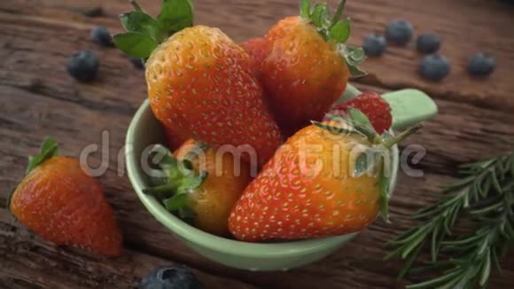 白色木制背景的白色碗中的多汁新鲜草莓视频的预览图