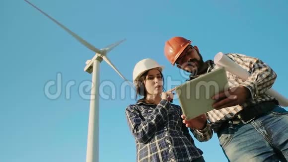 一个领域的两名工程师正在讨论同时看着平板电脑风力发电机在背景上慢慢视频的预览图