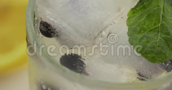 饮料杯里有柠檬薄荷叶冰块和黑加仑子的冷饮视频的预览图