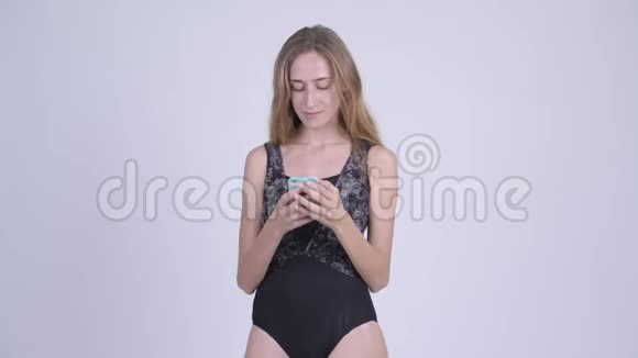 年轻的金发美女穿着泳衣一边打电话一边思考视频的预览图