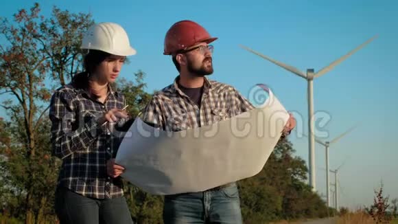 两位工程师在一张大纸上热烈讨论计划并做笔记后台有风力发电机视频的预览图