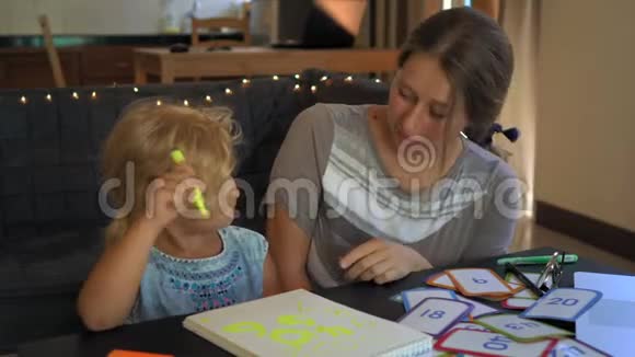 教师家庭教育的导师老师或妈妈和一个小女孩坐在桌旁家庭教育理念视频的预览图