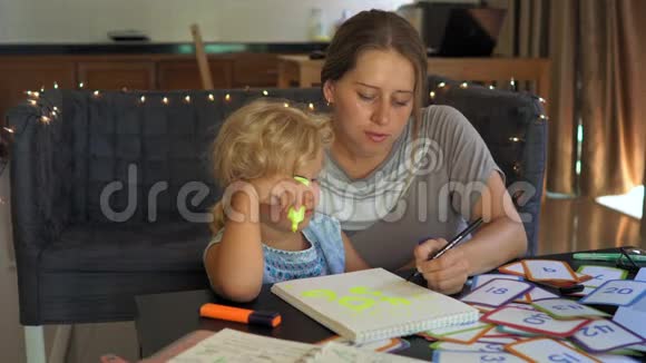 教师家教和一个小女孩在桌子上的老师或妈妈家庭教育概念视频的预览图