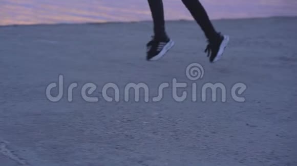 黑色运动裤和运动鞋女人的双腿在早晨沿着河岸的一条水泥路奔跑视频的预览图