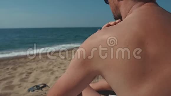 夏天一个人坐在沙滩上在皮肤上涂防晒霜视频的预览图