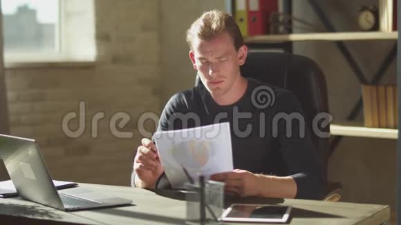 商务的年轻人坐在办公室笔记本附近的桌子上在文件上工作修改一下视频的预览图